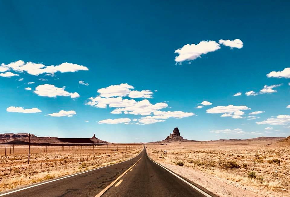 Partly cloudy skies over a road cutting through Monument Valley, Arizona