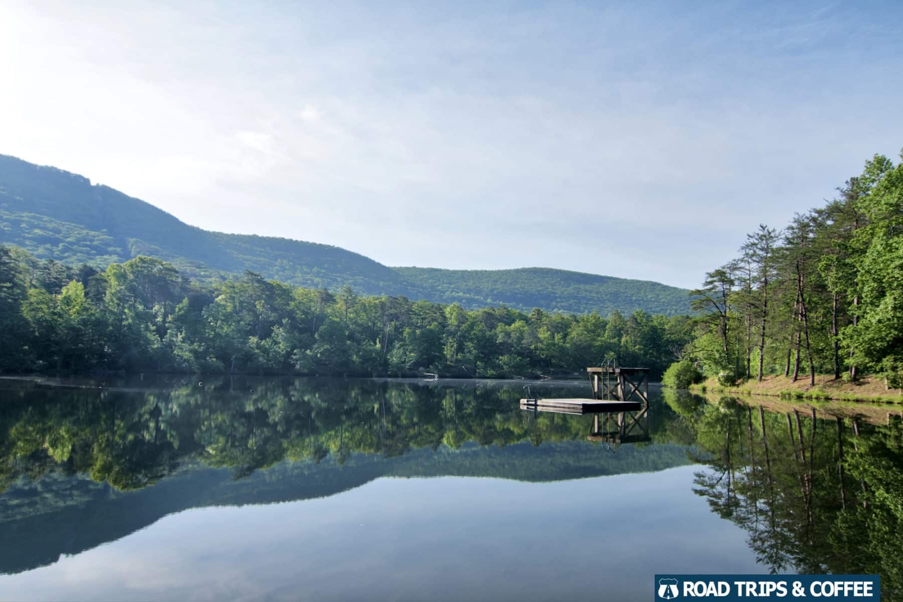 Perfectly calm water on a large lake reflecting the surrounding mountain and trees at Cheaha State Park in Alabama.