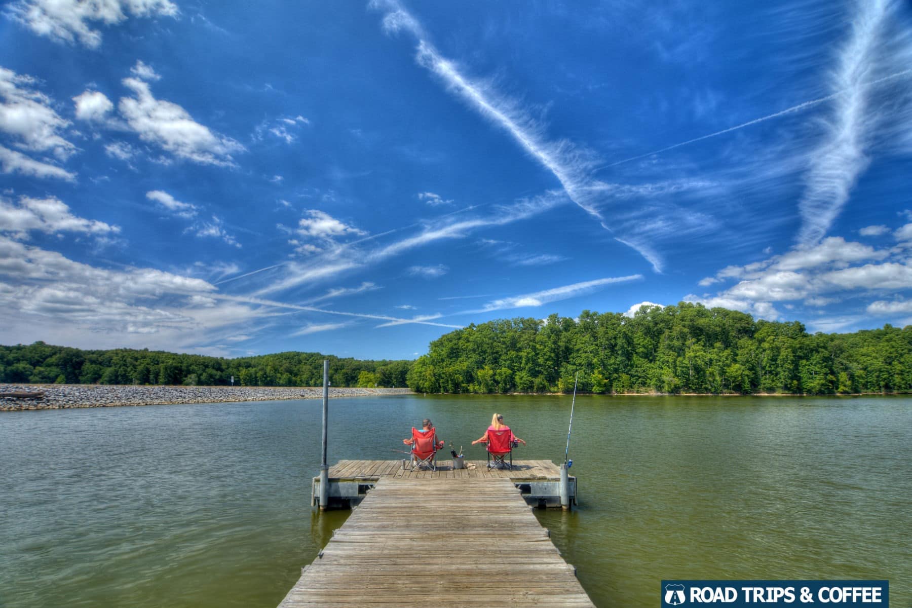 A man and woman sitting in bright red collapsible chairs on a pier fishing at the Energy Lake Day Use Area in Land Between the Lakes National Recreation Area