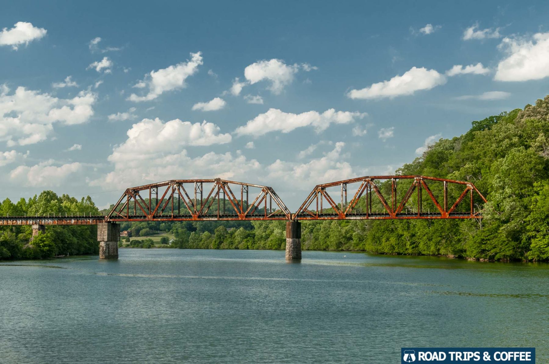 A rusty railroad bridge crosses the calm Melton Lake in Oak Ridge, Tennessee