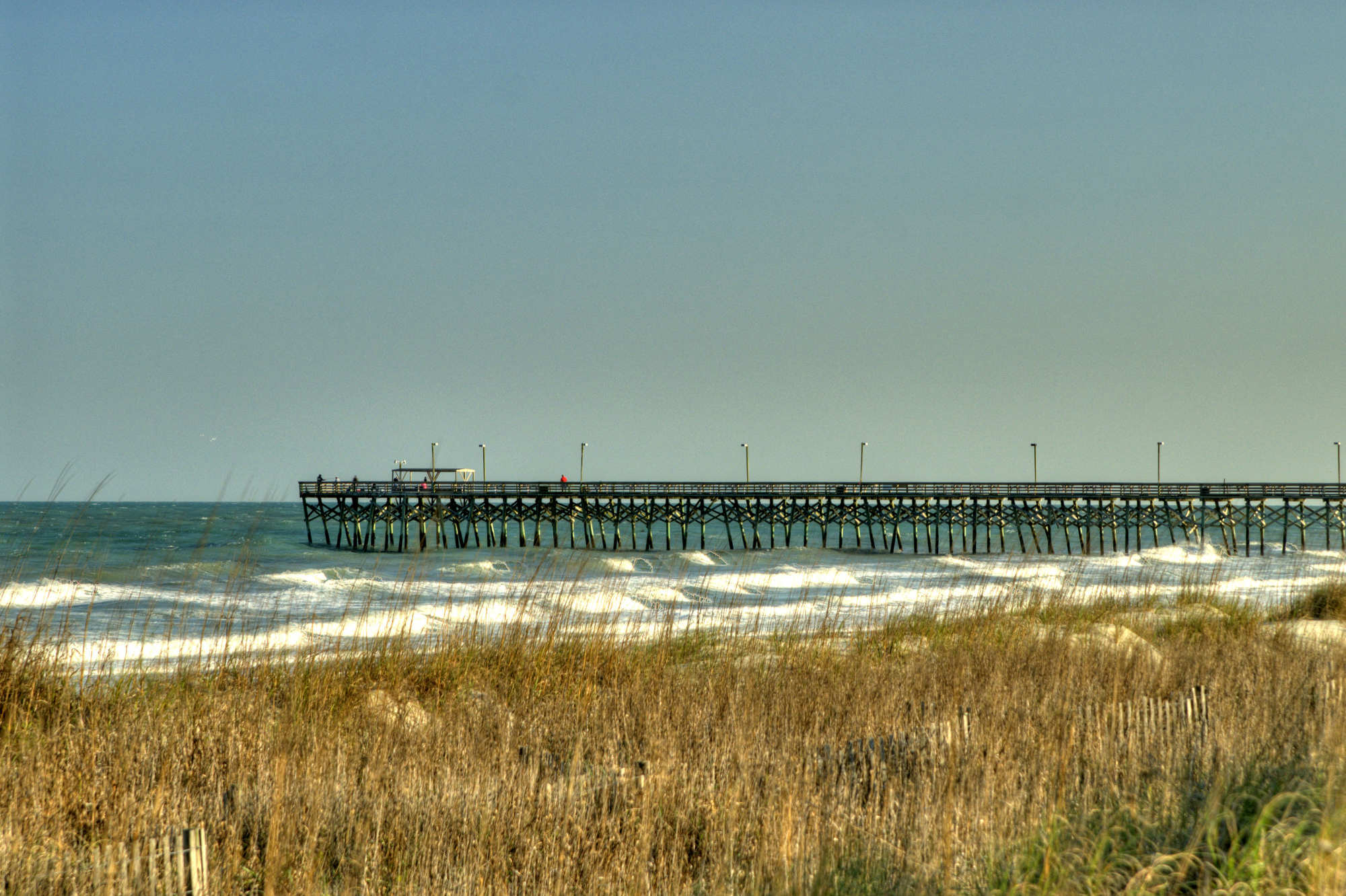 The long wooden Surfside Beach Pier stretches across the beach and ocean in Surfside Beach, South Carolina.