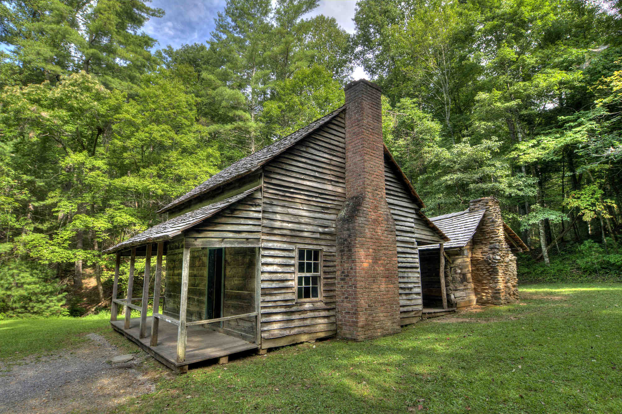 An old log cabin at the end of a gravel path in Cades Cove in Great Smoky Mountains National Park.