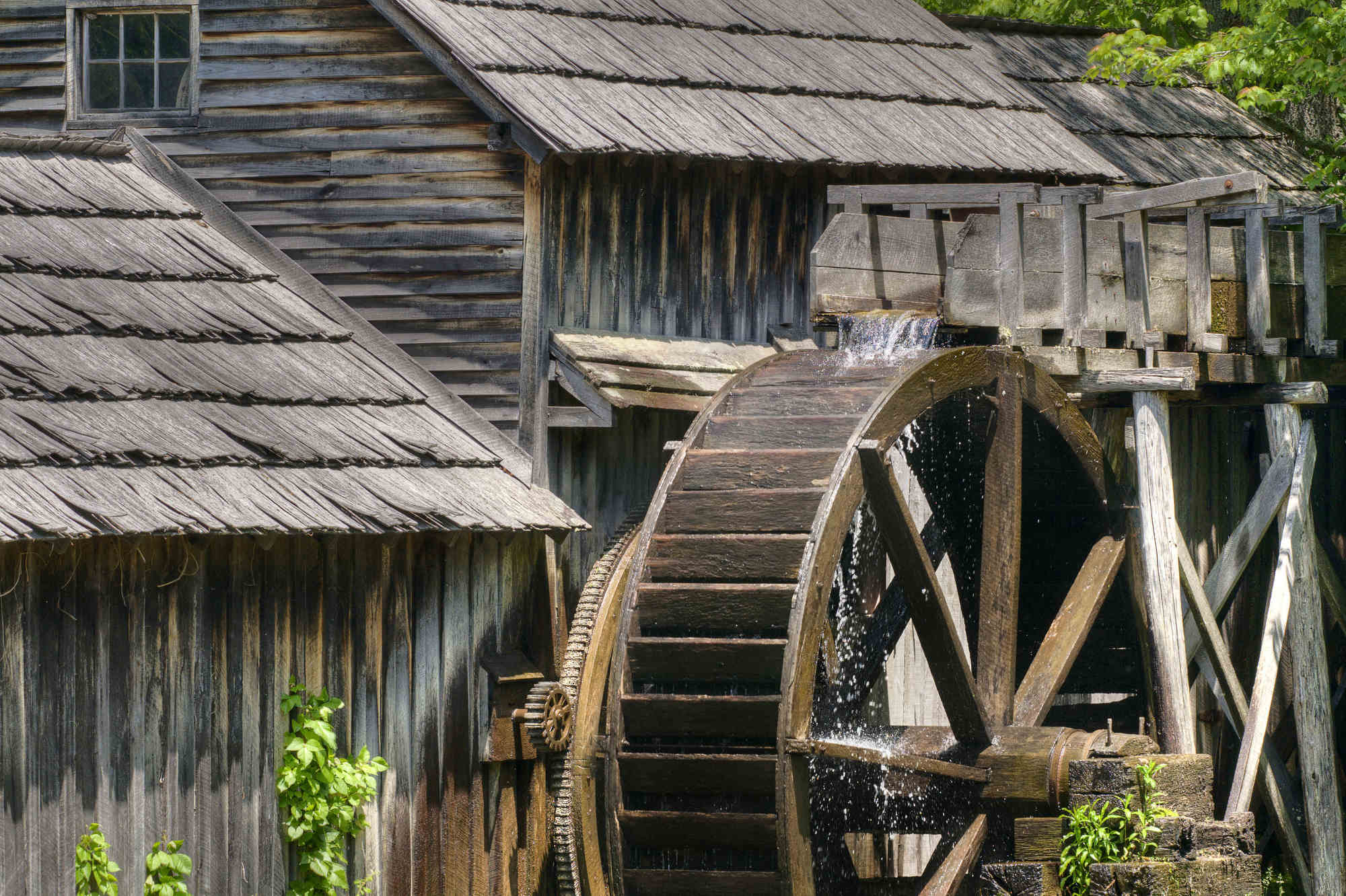 Water from a worn wooden aqueduct spills over the top of the wooden wheel at Mabry Mill on the Blue Ridge Parkway.